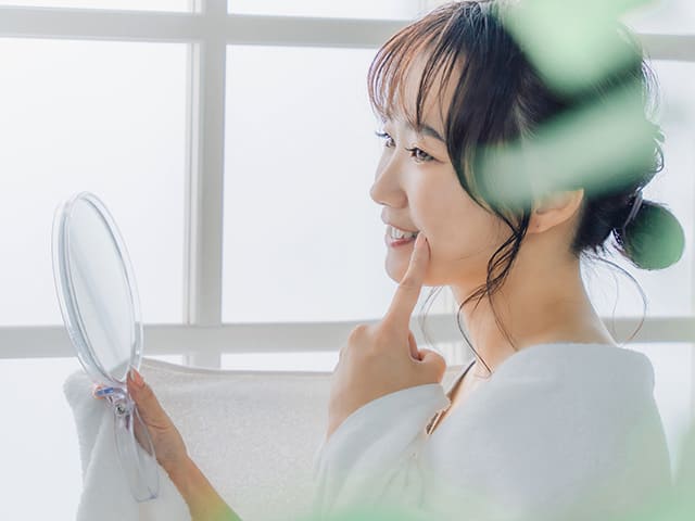 鏡で口元を見る女性