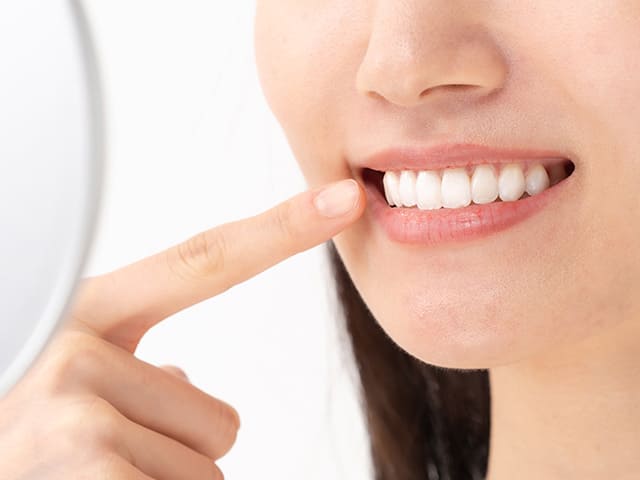 鏡で口元を見る女性